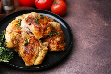 Tasty cooked chicken thighs with thyme and tomatoes on brown table, closeup. Space for text