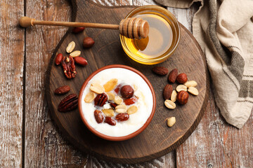 Delicious Greek yogurt with honey and nuts served on wooden table, flat lay