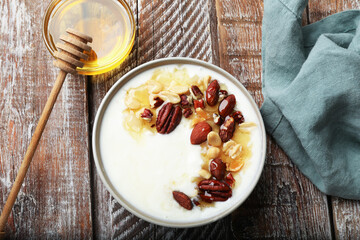 Delicious Greek yogurt with honey and nuts served on wooden table, flat lay