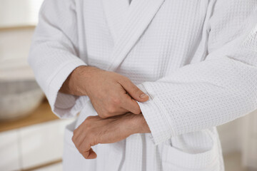 Man wearing comfortable white bathrobe indoors, closeup