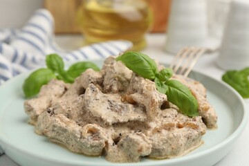Tasty beef Stroganoff with basil on table, closeup