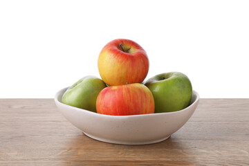 Red and green ripe apples in bowl on wooden table against white background