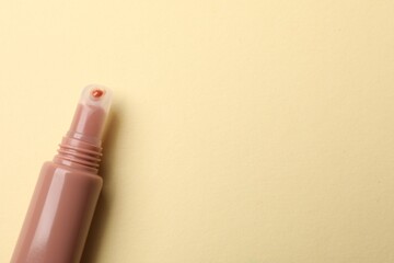 Beautiful nude lip gloss on beige background, top view. Space for text