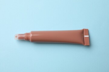 Beautiful nude lip gloss on light blue background, top view