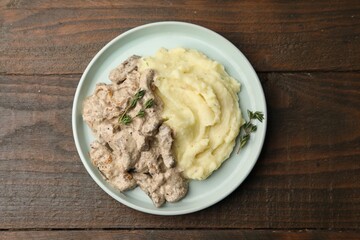 Delicious beef stroganoff with mashed potatoes and thyme on wooden table, top view