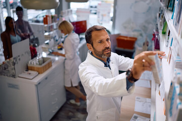 Male pharmacist checking inventory while working in pharmacy.