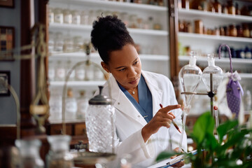 Black female pharmaceutical researcher working in pharmacy.