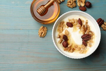 Delicious Greek yogurt with honey and nuts served on blue wooden table, flat lay. Space for text