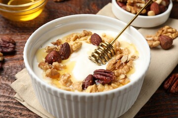Delicious Greek yogurt with honey and nuts served on wooden table, closeup