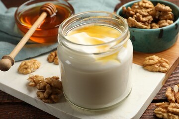 Delicious Greek yogurt with honey and walnuts served on wooden table, closeup