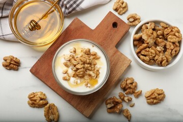 Delicious Greek yogurt with honey and walnuts served on white table, flat lay