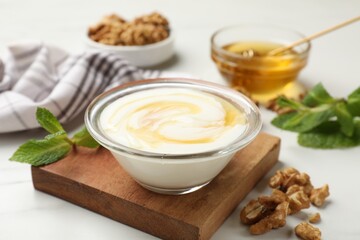 Delicious Greek yogurt with honey and walnuts served on white table, closeup