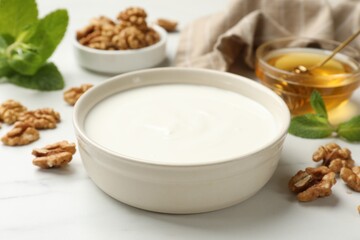 Delicious Greek yogurt with honey and walnuts served on white table, closeup