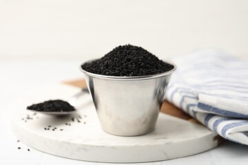 Aromatic black caraway in bowl and spoon on white table, closeup
