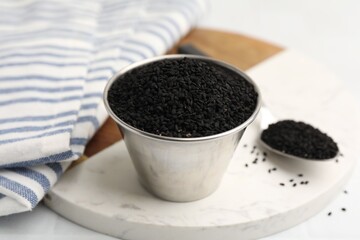 Aromatic black caraway in bowl and spoon on white table, closeup