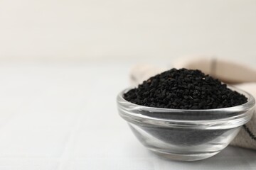 Aromatic black caraway in glass bowl on white table, closeup. Space for text