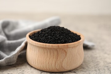 Aromatic black caraway in wooden bowl on grey table, closeup