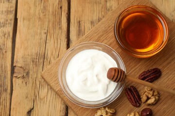 Delicious Greek yogurt with honey and nuts on wooden table, flat lay. Space for text