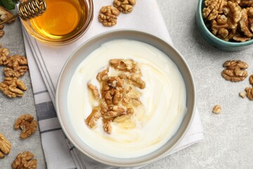 Delicious Greek yogurt with honey and nuts on light grey table, flat lay