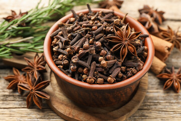 Different spices in bowl and fresh rosemary for mulled wine on wooden table, closeup