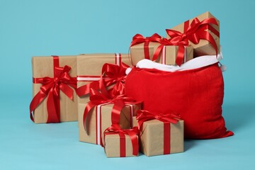 Fototapeta premium Santa Claus bag with Christmas gifts on light blue background