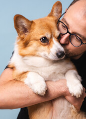 Young Man Holding a Cute Corgi Dog in a Portrait Shot