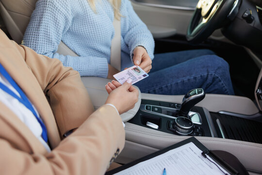Driving Test Instructor Verifying Student Driver&rsquo;s License Inside Vehicle