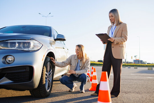 Confident driving instructor holding cones in parking lot during driver training