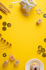 Colorful vertical Hanukkah scene with gift box, dreidel, menorah, coin and pastry on a vibrant...