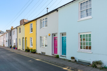 Terraced houses with colourful wooden front doors along a street in a city centre on a sunny spring...