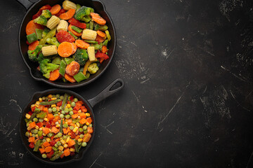 Frozen mixed vegetables two cast iron skillets black healthy cooking defrosting meal prep copy space