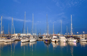 Fototapeta premium White sailboats and yachts moored in marina harbor at blue hour