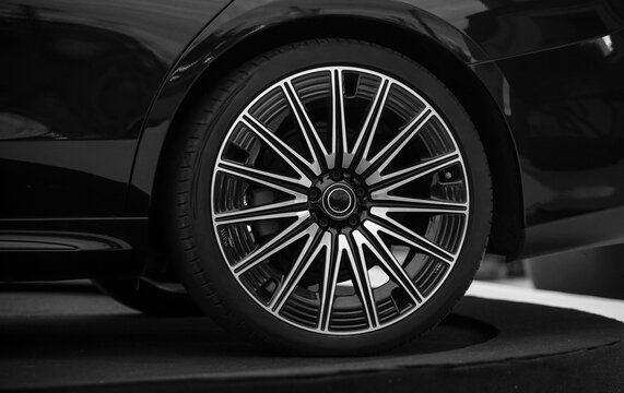 Fototapeta low profile tire Shiny alloy wheel of a luxury car silver black vehicle background Side Front view. chrome wheel automotive design, detail  elegance and speed. Metallic alloy rim, tire, and rubber