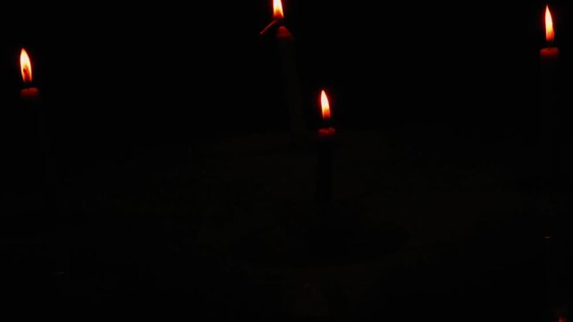 A candle burning in the dark, without electricity, darkness, ritual. Night space glowing softly with flickering light. Calm reflective mood.
