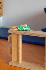 Wooden play equipment with green rope and wooden handles, designed for children's physical activity and development, enhancing motor skills and coordination in a playful environment