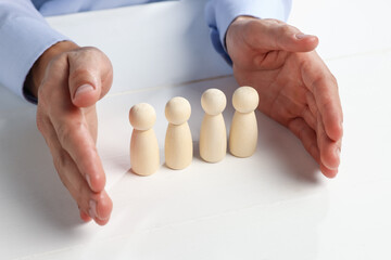 Obraz premium Man protecting human figures at white wooden table, closeup