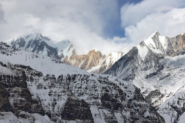Snowy mountains fill the frame, showcasing the majestic landscape of the Himalayas. This is a view within the Annapurna Sanctuary during the day in Nepal.