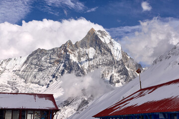 A majestic mountain dominates the skyline. It is viewed from a lodge near Annapurna Base Camp, in the Annapurna Sanctuary, Nepal. A sunny day reveals snowy mountain details.