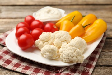Different fresh vegetables and sauce on wooden table, closeup