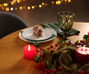 Christmas table setting with plates, glass and burning candles in festive decorated room, closeup