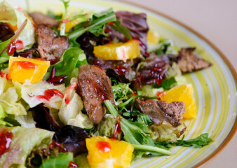 Salad with chicken liver, orange cherry sauce and arugula leaves Warm salad with fried chicken liver, cranberries and salad mix with orange dressing grey concrete. Healthy or diet food. . High quality