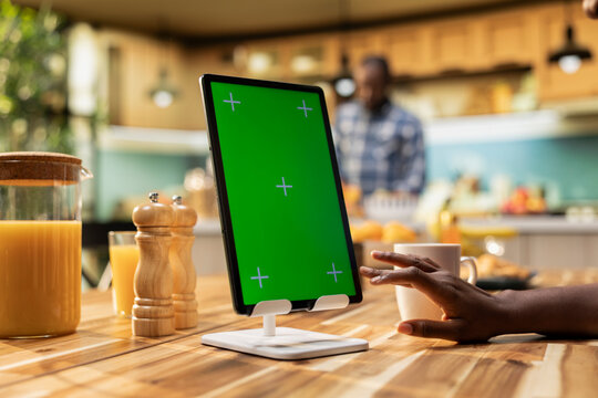 Chroma key vertical screen on tablet with African American woman at the table, enjoying a casual breakfast at home in the kitchen. Serving healthy food and coffee, illustrating cozy morning.