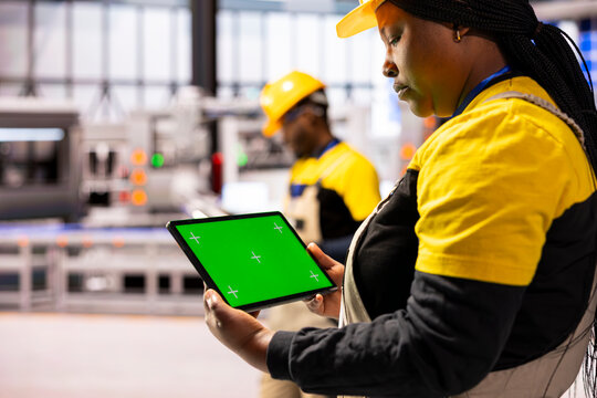 Black female production engineer using tablet with blank mockup template and inspecting a factory. African American industrial manager holding green screen device, monitoring system performance.