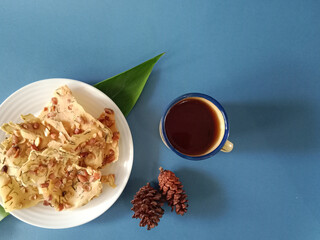 Top view of crunchy Indonesian traditional crispy peanut crakers known as rempeyek kacang and hot tea in a simple flat lay composition.