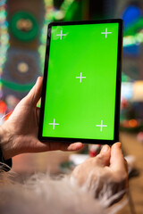 Obraz premium Close up of Santa Claus using mockup digital tablet to check naughty and nice kids list. Santa analyzes children behavior, preparing gifts for good children using green screen touchscreen device