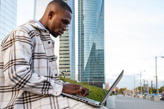 Urban workspace where a focused young man types on a laptop in a modern city setting