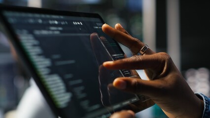 Close up of server room programmer checking coding on tablet enhancing operational efficiency and reducing downtime. Developer verifying programming language script used to update gear, camera B