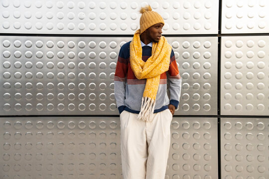 Fashionable individual showcases cozy winter style against modern backdrop in urban setting