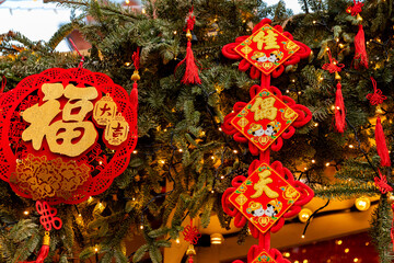 Naklejka premium Chinese-style Christmas tree toys and lights on green Christmas tree. Festive background. Chinese New Year in Moscow. High quality photo