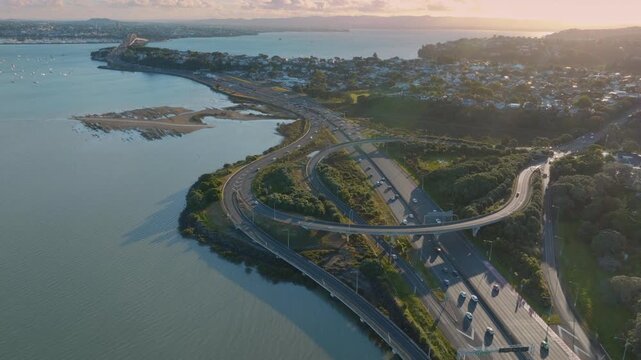 Aerial view of Northcote, Auckland, New Zealand, showing the Harbour Bridge and motorway. Cars are traveling along the highway, connecting different parts of the city.